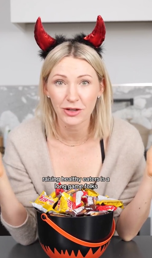 Dietitian Abbey Sharp in front of a bowl of Halloween candy